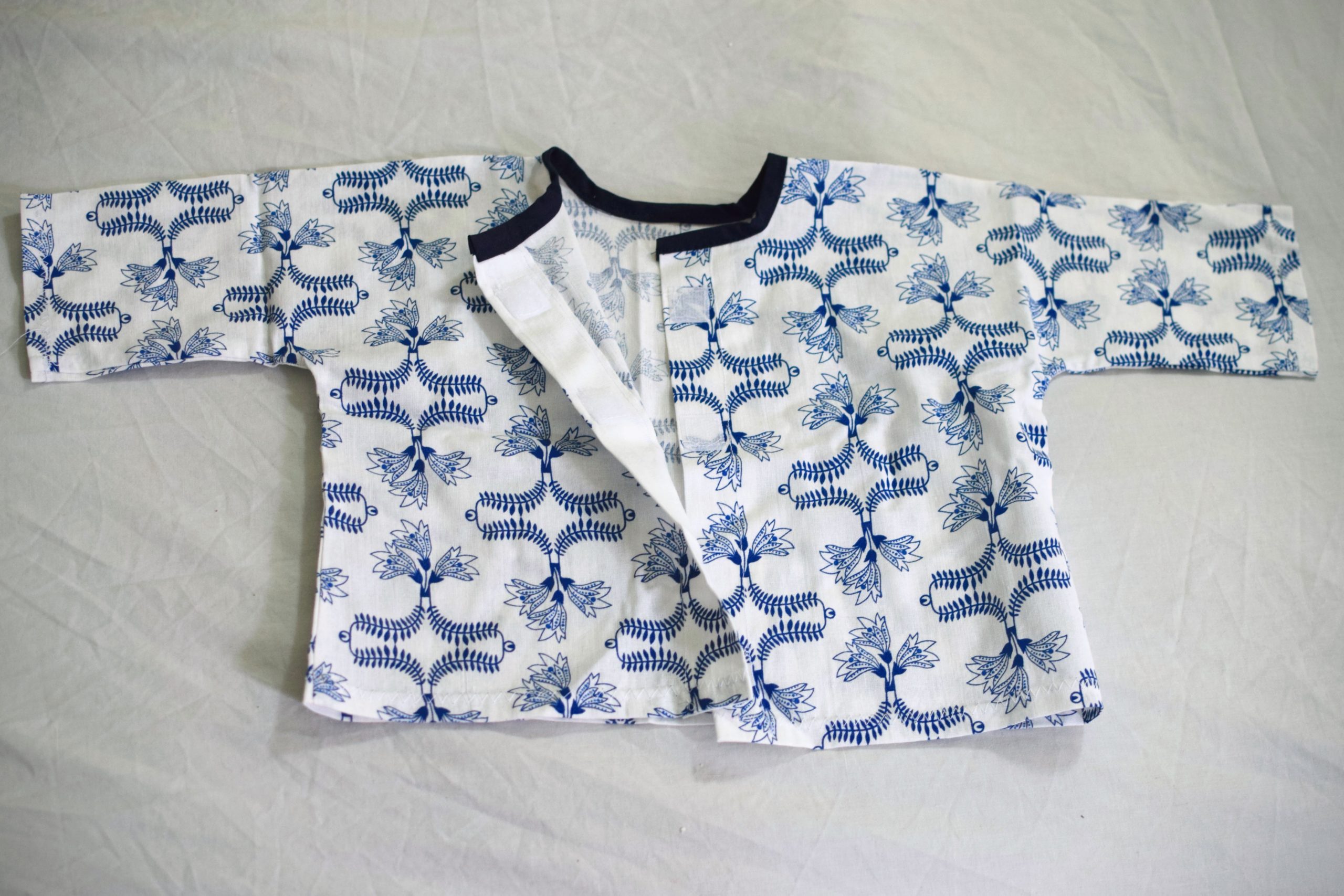 A hand-sewn baby shirt with velcro opening