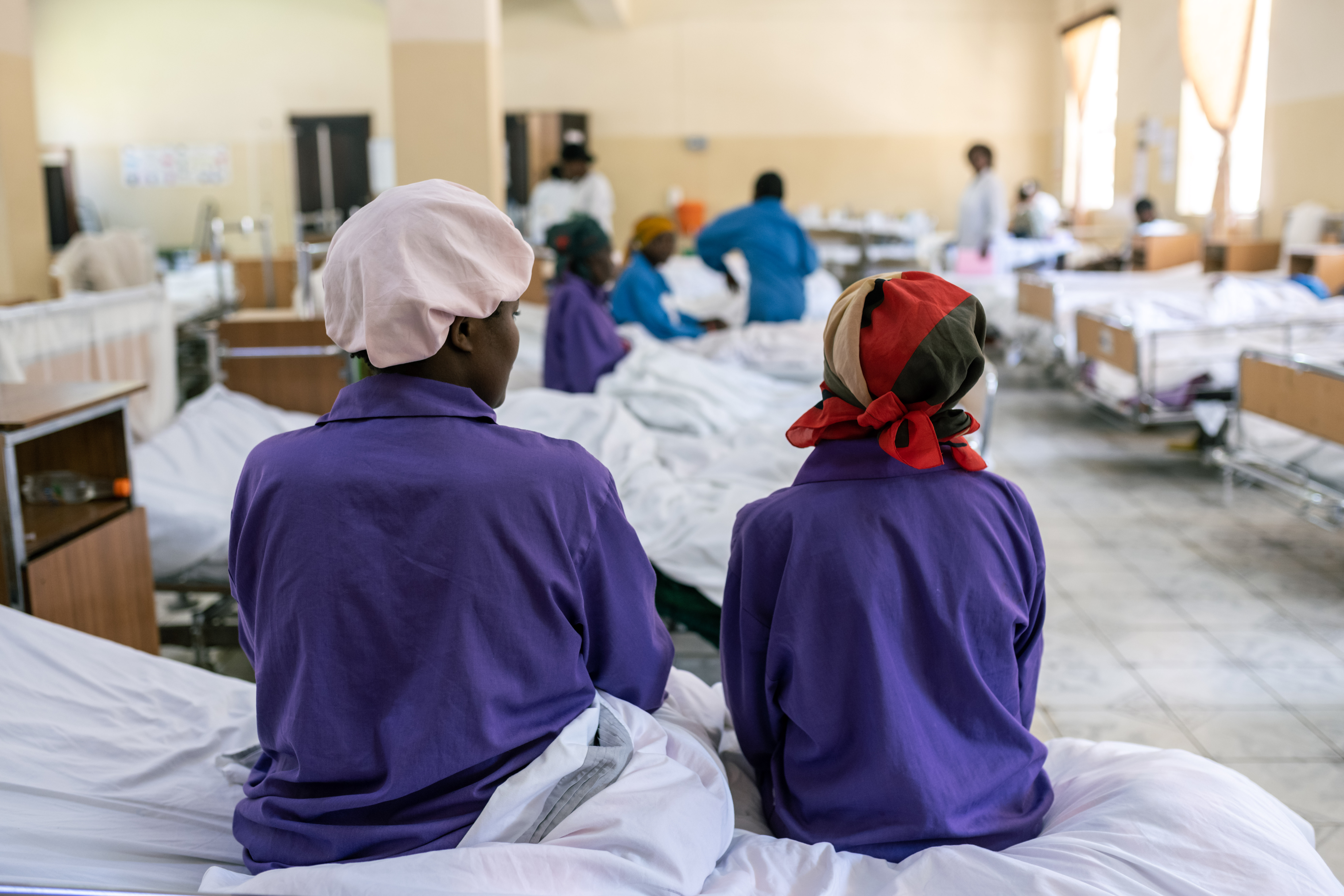 Two women sitting on hospital beds facing away from the camera.